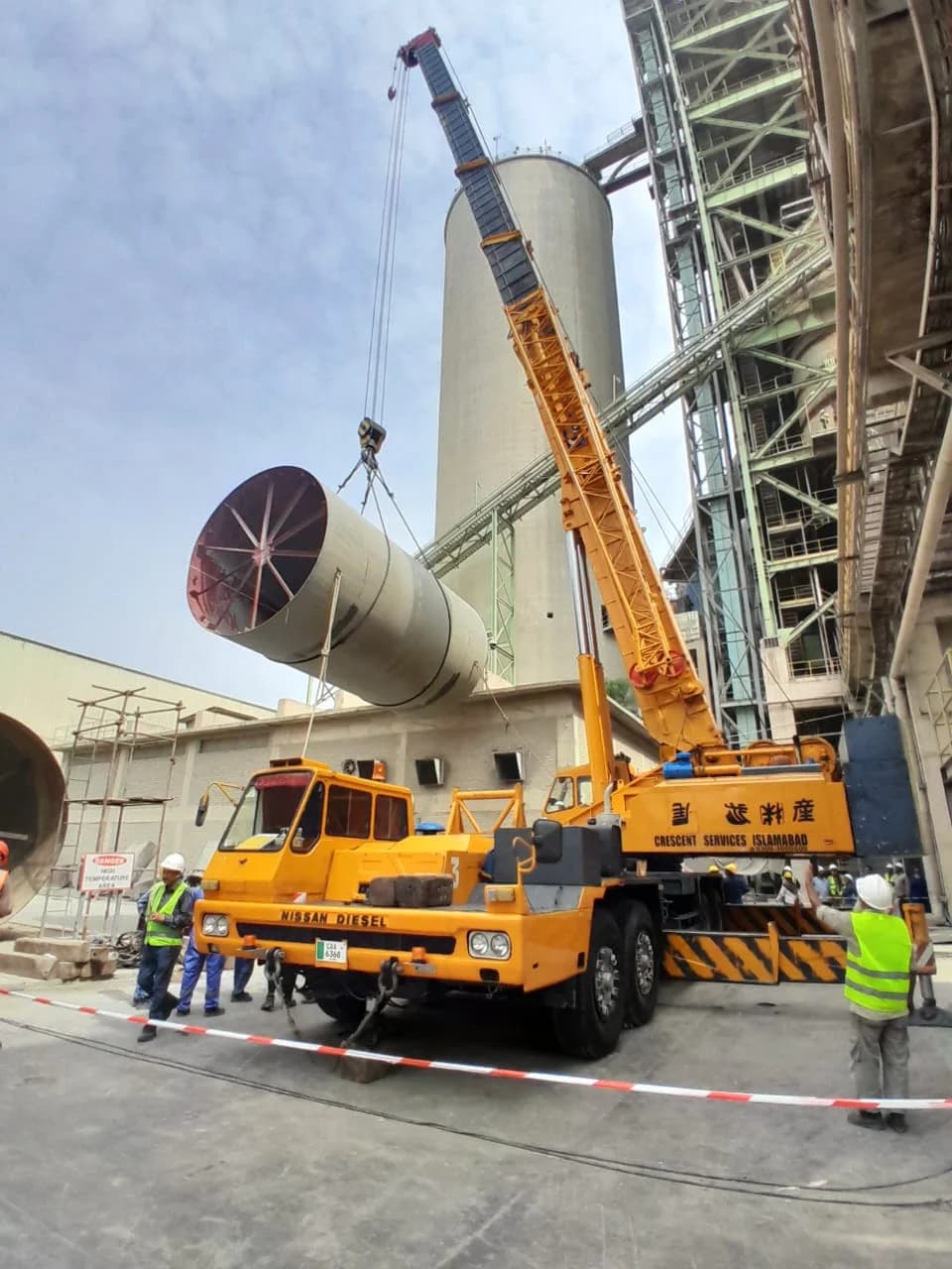 Mobile crane lifting heavy equipment at an industrial site