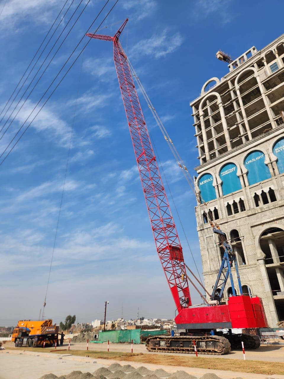 Red crawler crane beside a high-rise building